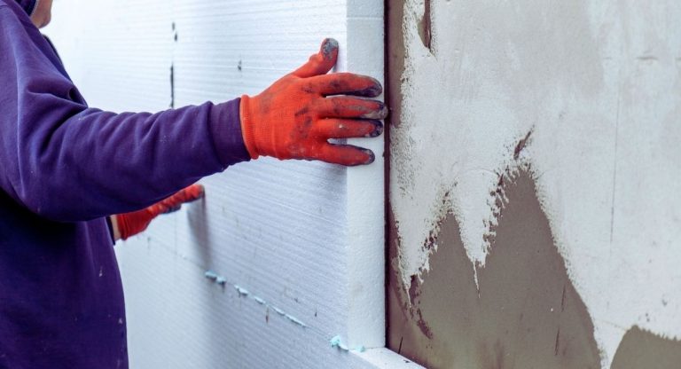 Ouvrier posant des panneaux d'isolation sur un mur exterieur de maison