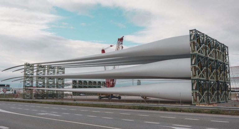 Grandes pales d'eolienne stockees sur un rack pres d'une route