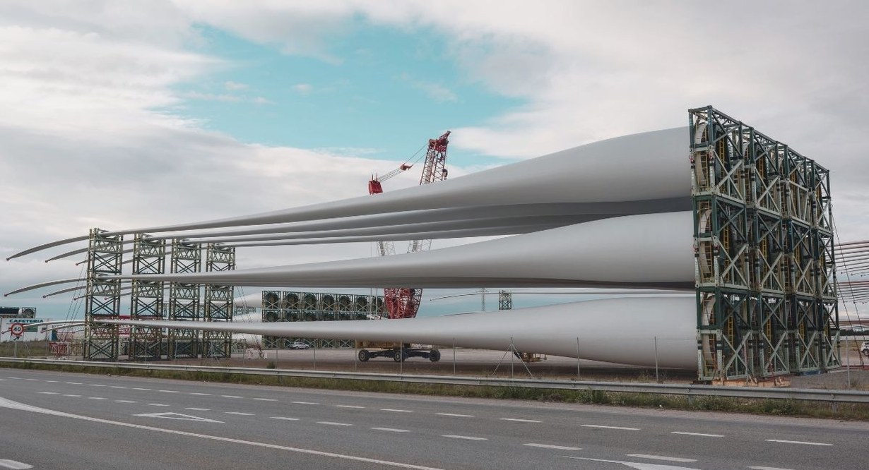 Grandes pales d'eolienne stockees sur un rack pres d'une route