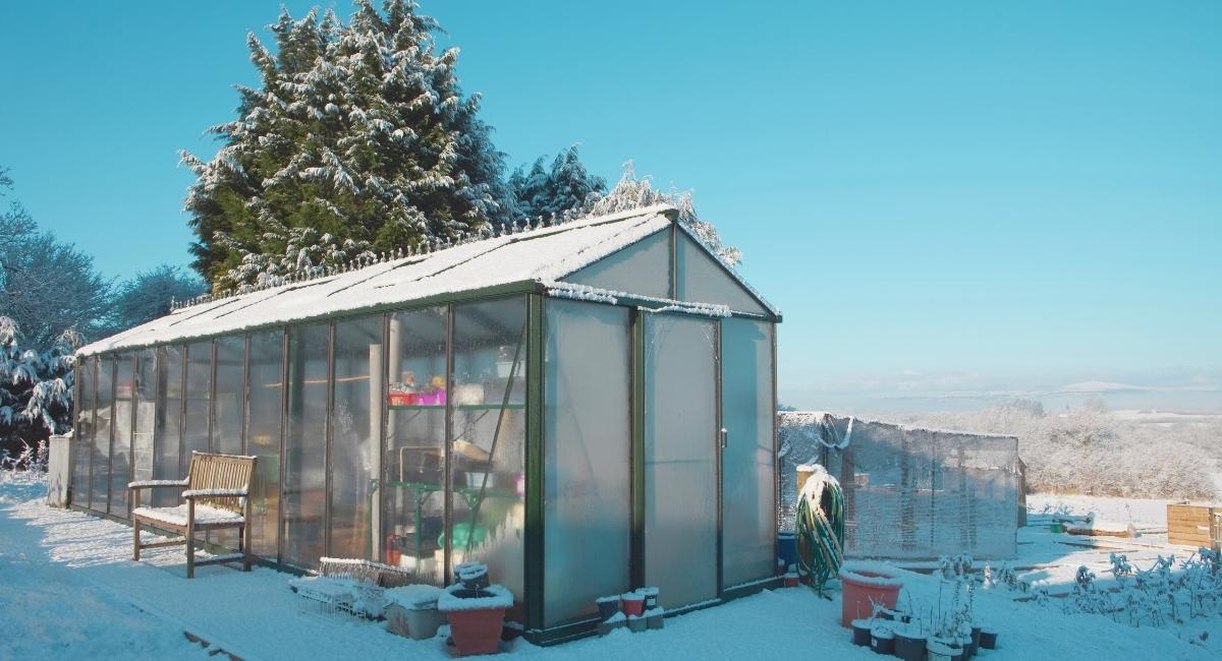 Serre de jardin recouverte de neige un matin d'hiver